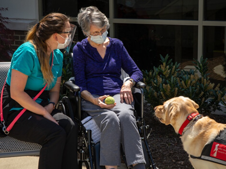 Two women outside with a therapy dog