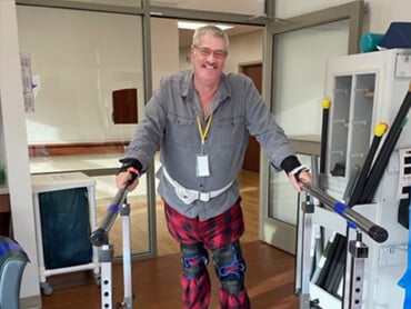 Frank Busch walks in the parallel bars during therapy.
